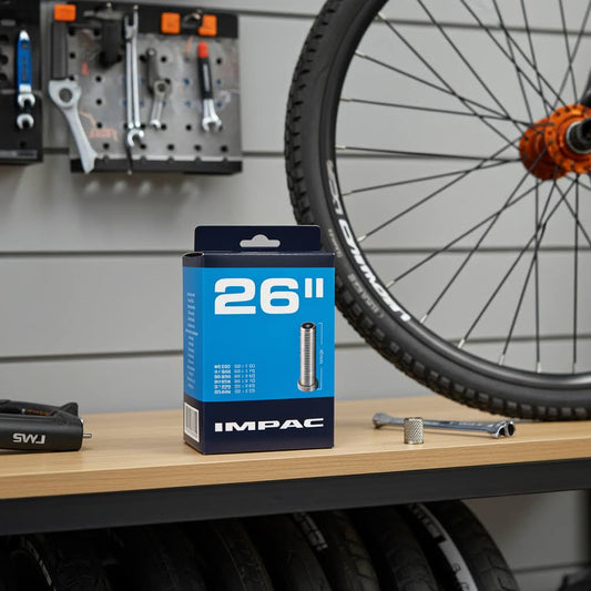 Box of 26-inch IMPAC bicycle tires on a workbench with a bike wheel in the background.